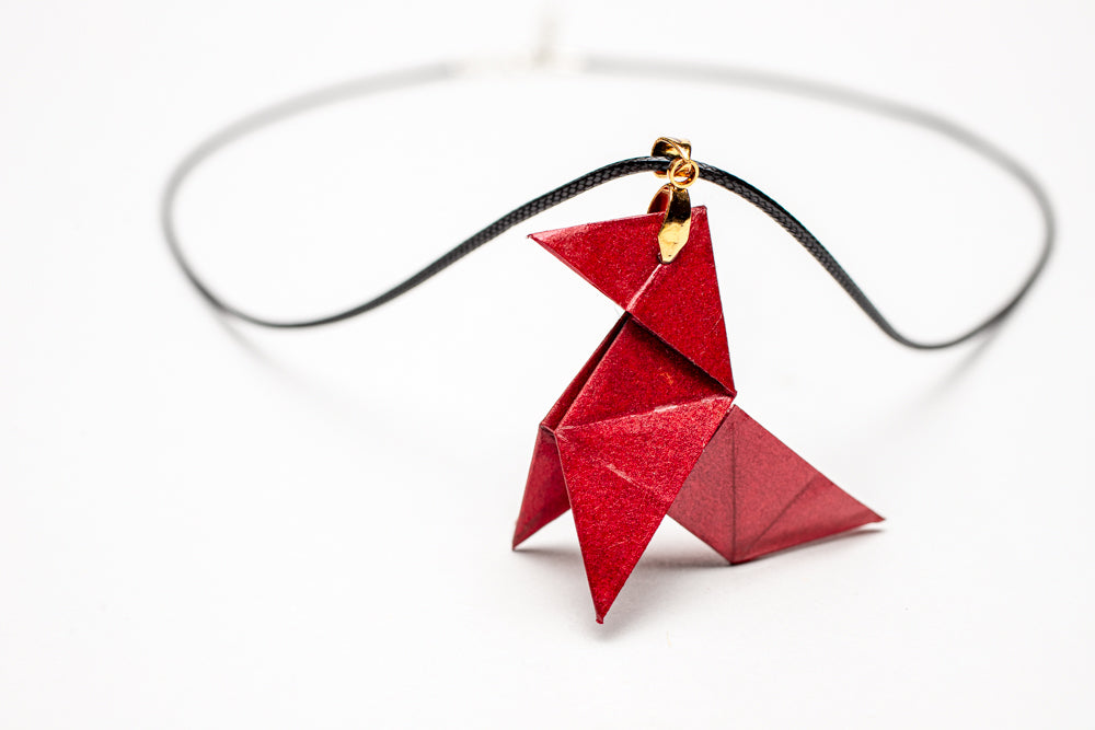 Colgante origami artesanal en papel rojo inspirado en La Casa de Papel sobre fondo blanco