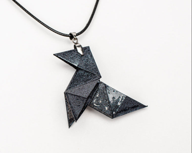 Colgante origami artesanal en papel azul inspirado en La Casa de Papel sobre fondo blanco