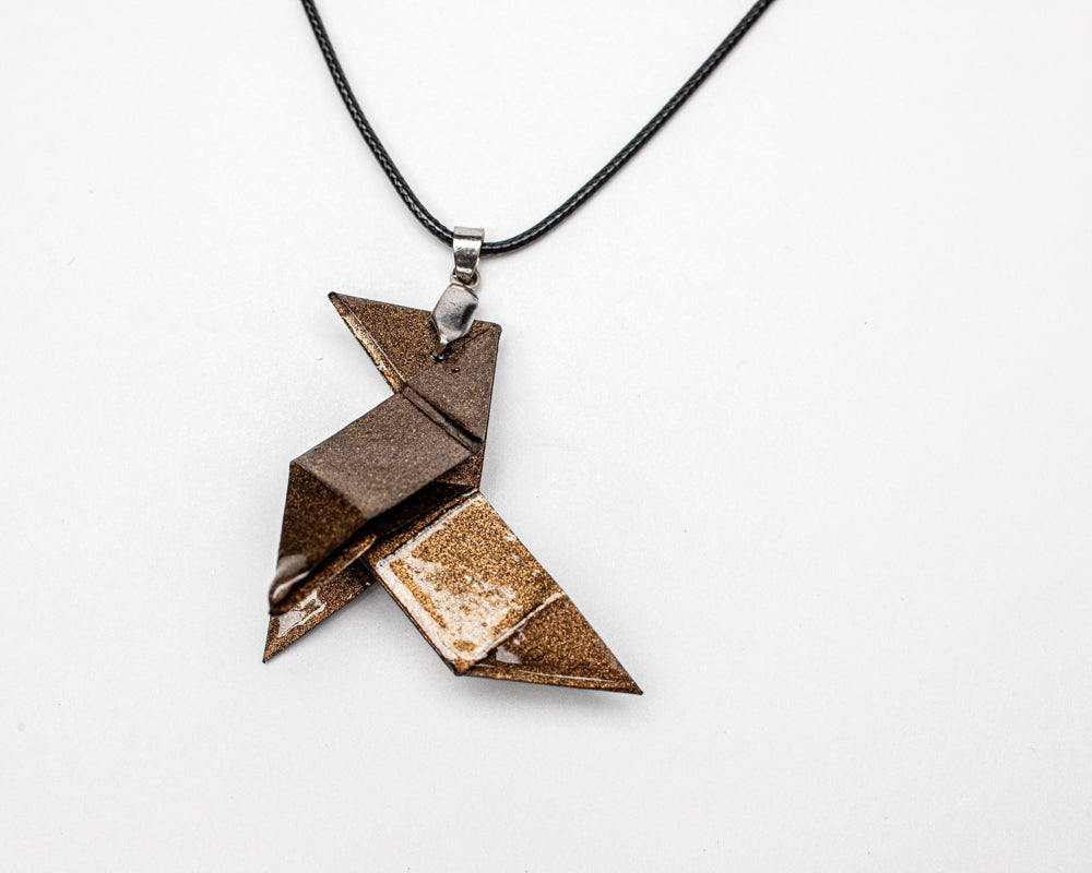 Colgante origami artesanal en papel bronce inspirado en La Casa de Papel sobre fondo blanco