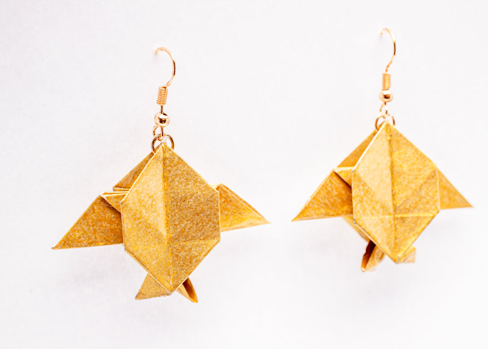 Aretes origami en forma de peces Luna dorados con acabado tornasolado sobre fondo blanco