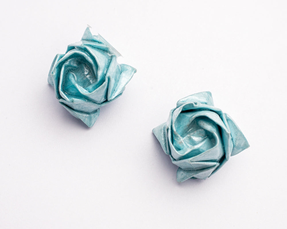 Topitos artesanales en forma de rosas en papel metálico azul sobre fondo blanco