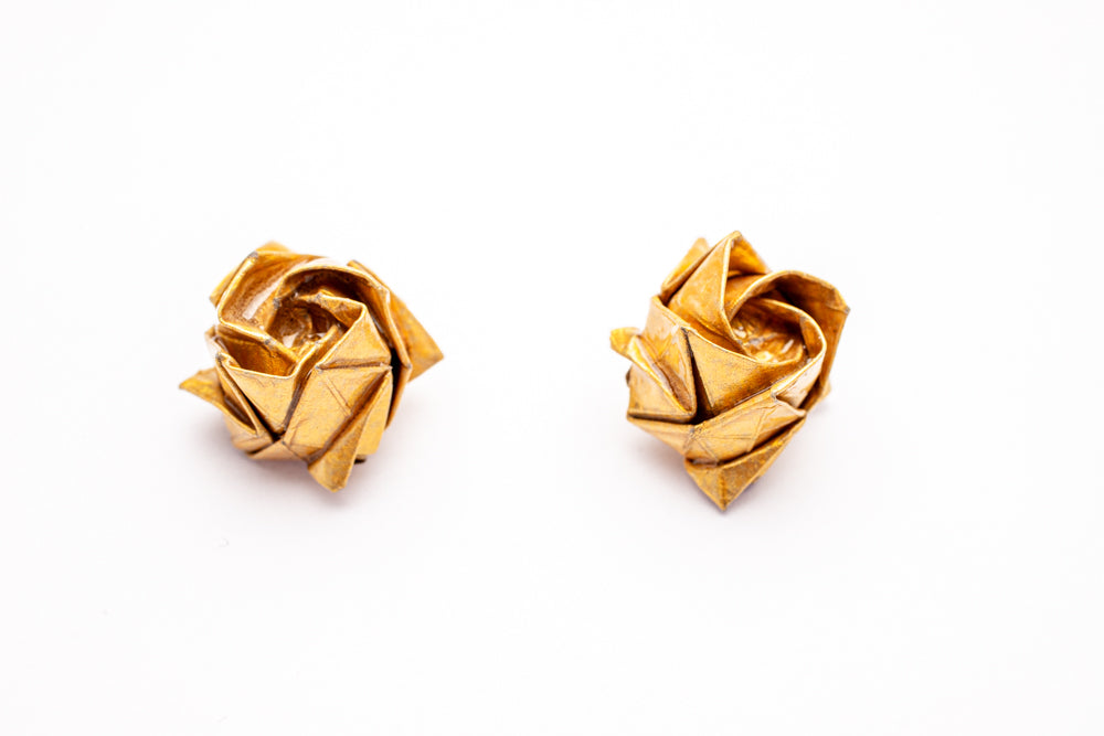 Topitos artesanales en forma de rosas en papel metálico dorado sobre fondo blanco