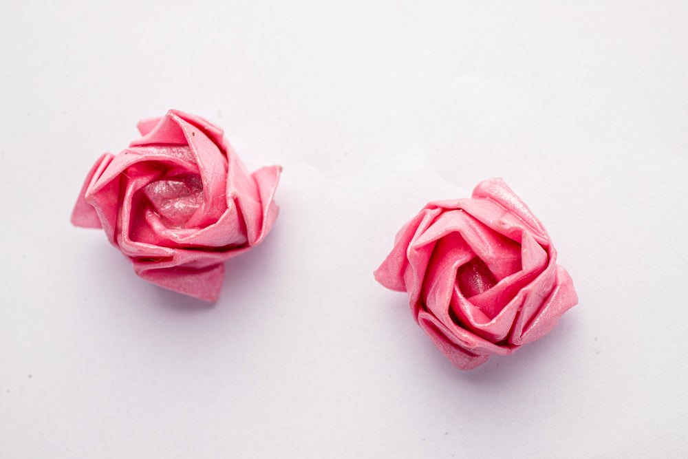 Topitos artesanales en forma de rosas en papel metálico rosa sobre fondo blanco